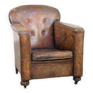 Fauteuil ancien en cuir de mouton sur roulettes et patiné