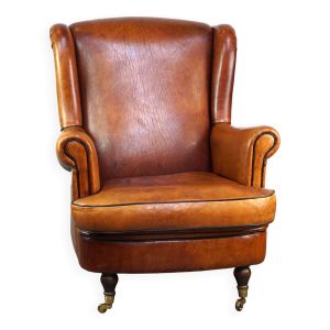 Fauteuil en cuir de mouton subtil et bien entretenu sur roulettes avant en laiton
