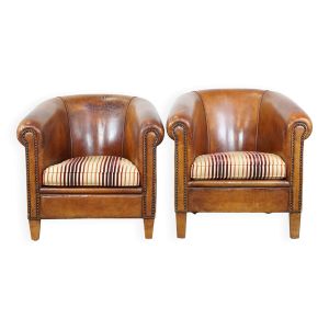 2 fauteuils club en cuir de mouton cognac et coussins en tissu coloré